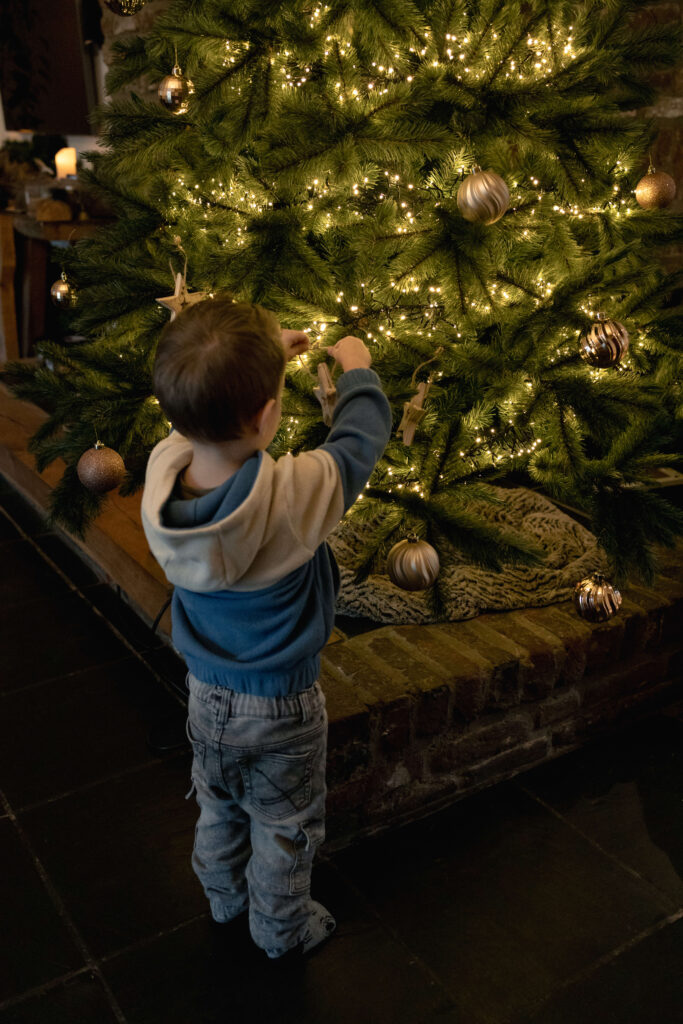 Zoon hangt kerstbal in boom