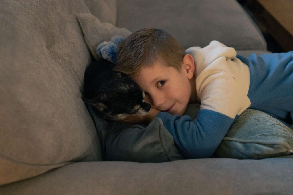 Jongen en hond knuffelen op de bank