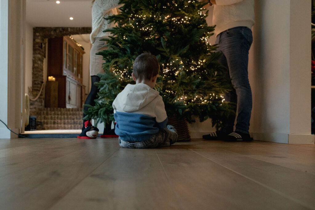 Vader en moeder tuigen kerstboom op samen met zoon
